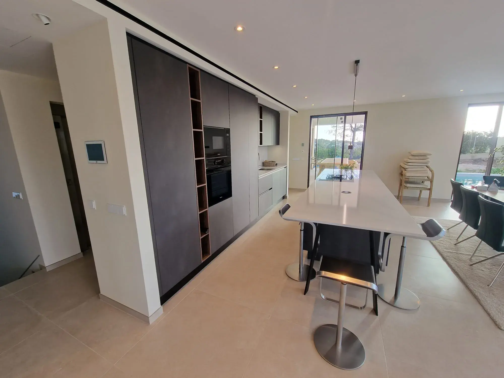 Moderne Designküche mit Kochinsel, grifflosen Fronten und integriertem Sitzbereich - von der Seite