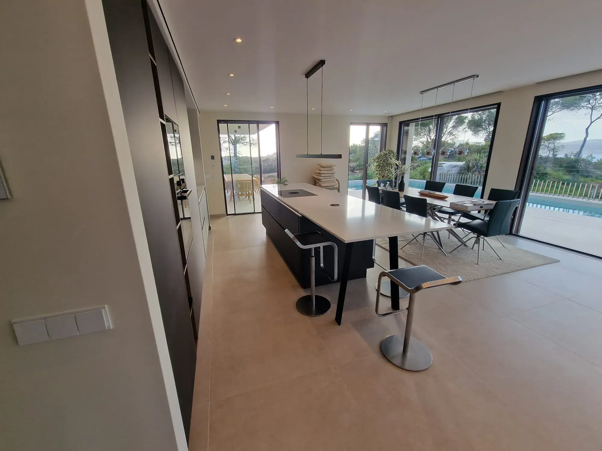 Moderne Designküche mit Kochinsel, grifflosen Fronten und integriertem Sitzbereich - mit Blick zum Fenster
