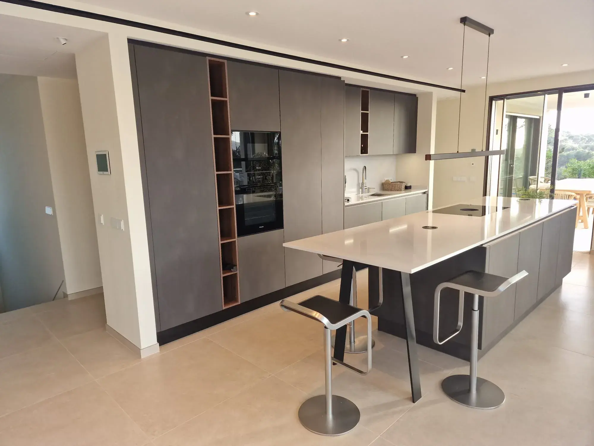 Moderne Designküche mit Kochinsel, grifflosen Fronten und integriertem Sitzbereich - von der linken Seite aus fotografiert